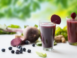 healthy eating, drinks, diet and detox concept - glass of beetroot juice with different fruits and vegetables on table over green natural background