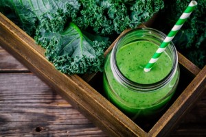 Healthy green smoothie with kale in mason jar on rustic wooden background