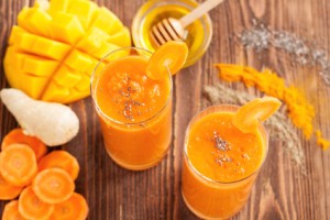 Smoothie with carrot, turmeric, mango, ginger, honey, chia seedss and spices on rustic wooden table